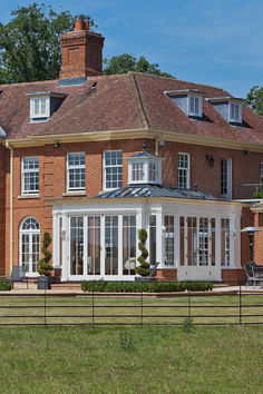 a large red brick house with white trim on the roof and windows, surrounded by green grass