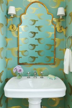 a white sink sitting under a mirror next to a wall mounted faucet in a bathroom