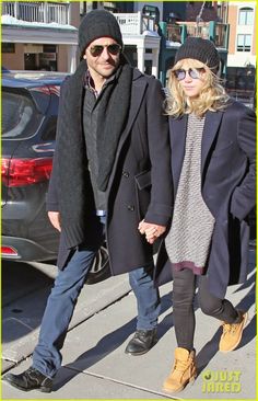 a man and woman holding hands while walking down the street