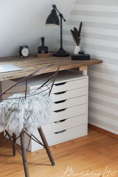 a desk with a chair, lamp and drawers in the corner on top of it