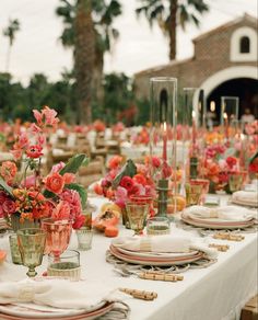 the table is set with flowers and candles for an elegant dinner party or reception in front of palm trees