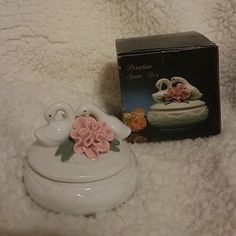 there is a small white box with pink flowers on it next to a figurine