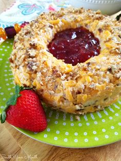 a plate topped with a pastry covered in toppings next to a bowl of fruit