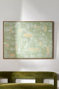 a green couch sitting in front of a painting on the wall