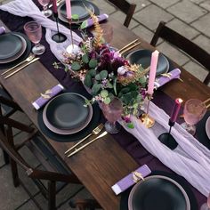 the table is set with black plates and purple napkins