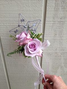 a person is holding a pink rose and silver star boutonniere