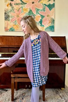 a woman standing in front of a piano with her hands out to the side and arms outstretched