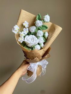 a hand holding a bouquet of flowers made from crocheted wool and yarns