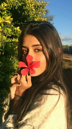 a woman holding a flower up to her face