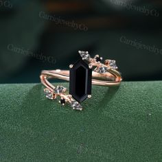 an image of a black diamond ring on green surface with gold and diamonds around it