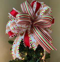 a christmas tree decorated with red, white and green ribbons on it's top