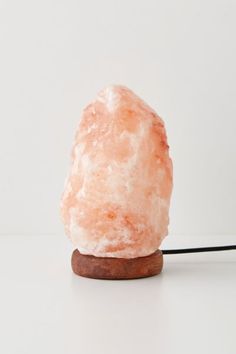 a large pink rock sitting on top of a wooden stand next to a white wall