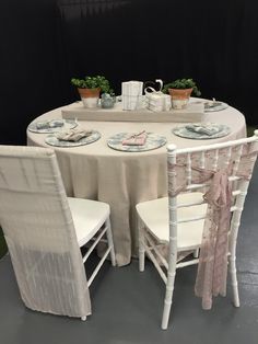 the table is set with white chairs and plates