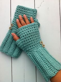 a woman's hand wearing a green crochet glove with buttons on it