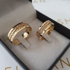 two gold rings sitting in a box on top of a table