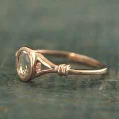 a gold ring with a faceted stone on the front and side, sitting on top of a piece of wood