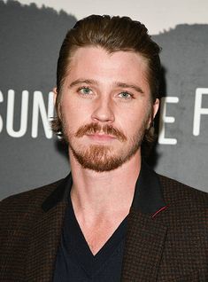 a close up of a person wearing a suit and tie with a goatee on