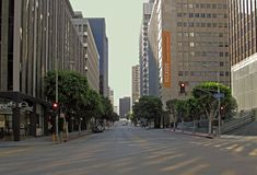 an empty city street with tall buildings on both sides and trees in the middle of the road