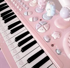 a pink musical keyboard with many different items on it and a teddy bear figurine next to it