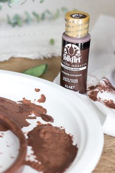 a white plate topped with chocolate frosting next to a bottle of paint