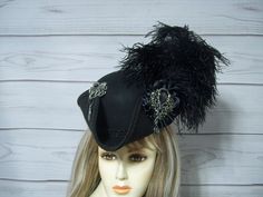 Ladies black woolen MINI pirate hat with black ostrich feathers on the left side of the hat, black cocarde with a large sparkly jewel, metal octopus charm with a pirate charm dangle.  There is an elastic strap that goes under your hair at the nape of your neck. This hat is more of a 3/4 size hat that sits on top of your head and not down on your head like a regular hat. The hat measures about 11"x10" wide. The inside circumference is 21" All sales are FINAL, no returns or exchanges please keep this in mind before purchasing. Please let me know if you have any questions International buyers: Please know that you will be held responsible for any CUSTOMS FEES. Please check with you local post office, before ordering to see what the customs fee rate is before you purchase Pirate Hat Women Feathers, Pirate Hat Fancy, Pirate-style Brimmed Costume Hat, Vintage Black Hat For Costume Party, Black Brimmed Mini Hat For Costume Party, Black Brimmed Hat With Feather Trim, Black Mini Hat With Feathers And Curved Brim, Black Pirate Costume Hat With Curved Brim, Black High Crown Hats For Costume Party