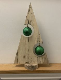 two green and white ornaments on top of a wooden shelf in front of a wall