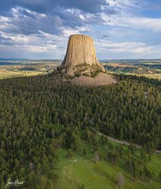 an aerial view of a large rock formation in the middle of a green field and trees