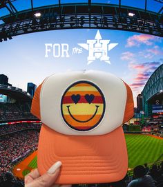 a baseball cap with a smiley face on it in front of a stadium full of people