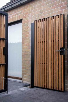 two wooden doors on the side of a brick building next to a black metal door