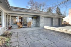 a house that has some chairs in front of it and a patio with stone pavers