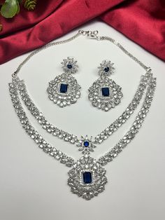 Gorgeous fine quality replica diamond and CZ blue studded necklace with a white  rhodium plating and matching Earrings Item contains: Necklace and earrings AAA-quality cubic zirconia was used. Highest quality and craftsmanship Necklace Fitting is adjustable Earrings Closure: Pushback Necklace Closure: chain with Hook Formal Cubic Zirconia Jewelry Sets With Stone Work, Silver Cubic Zirconia Jewelry Sets With Stone Setting, Blue Jewelry With Stone Work For Reception, Blue Stone Work Jewelry For Reception, Blue Hand Set Bridal Necklace For Reception, Traditional Blue Jewelry Sets For Reception, Traditional Blue Jewelry For Reception, Blue Diamond Jewelry Sets For Wedding, Blue Stone-set Wedding Jewelry