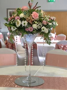 a vase filled with flowers sitting on top of a white table cloth covered dining room