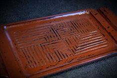 a brown tray with holes in it sitting on a table next to a black floor