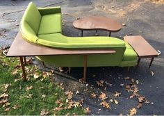 a green couch sitting on top of a wooden table next to a small coffee table