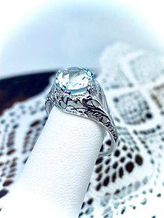 Introducing our elegant and timeless Natural Aquamarine Ring, crafted from 925 sterling silver and featuring a stunning 1.5ct AAA quality natural aquamarine gemstone. This ring is a reproduction of a classic Art Deco design, exuding vintage charm and sophistication. The light blue aquamarine stone measures 8mm in diameter and is of superior quality. The band is marked with 925 for sterling silver, ensuring its authenticity and quality. The intricate filigree setting showcases the expert craftsma Classic White Sapphire Gemstone Ring, Classic White Sapphire Ring With Accent Stones, Silver Blue Topaz Diamond Cut Ring, White Topaz Ring With Accent Stones In Classic Style, Classic Sterling Silver Topaz Ring With Brilliant Cut, Classic Blue Topaz Diamond Cut Ring, White Sapphire Sterling Silver Ring, Classic Sterling Silver Topaz Ring, Classic Sterling Silver Round Topaz Ring