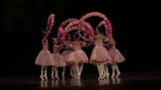 a group of ballerinas in pink tutu skirts performing on stage with their arms raised