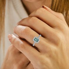 a woman's hand with a ring on it and an emerald stone in the middle