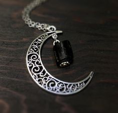 This beautiful crescent moon necklace will inspire all your moonlit nights. This made to order necklace features silver toned metals and a black tourmaline gemstone. product details Silver tone metals Choose your chain length Black tourmaline gemstone; Each piece is unique. The stone varies but is roughly 1/4 inch long or smaller. Each stone is natural and unique. Metaphysical properties of black tourmaline: One of the only stones that heals and protects on all levels, physical, mental, spiritua Gothic Crescent Moon Charm Jewelry, Witchy Moon Phase Jewelry Gift, Gothic Crescent Moon Phase Jewelry, Goth Necklace, Crescent Moon Necklace, Creating Jewelry, Tourmaline Gemstone, Buy Handmade, Moon Necklace