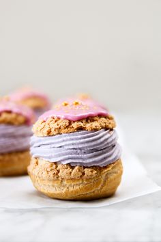 two donuts with frosting and sprinkles on them sitting on a piece of paper