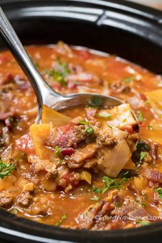 a ladle full of soup with meat and vegetables in it is being lifted from the slow cooker