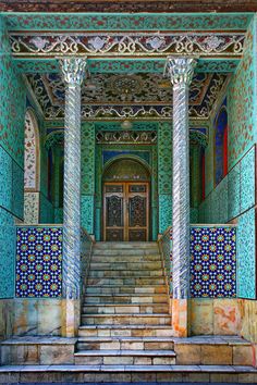 an ornate building with blue and green tiles on the walls, stairs and door to another room