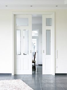 an empty room with two doors and a rug on the floor