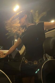 a woman sitting in the back of a car with her hair blowing in the wind