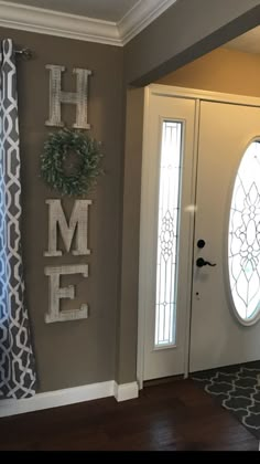 a door with the word home painted on it next to a wreath and window sill