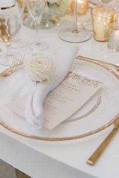 a table set with white and gold place settings