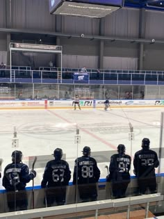 hockey players are lined up on the ice at an indoor rink, waiting for their turn to play