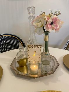 a white table topped with plates and vases filled with flowers on top of it