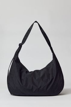 BAGGU large nylon crescent bag. BAGGU’s crescent bag in a larger size that’s effortlessly casual and roomy enough to carry more than just the essentials. Comfy BAGGU shoulder bag silhouette with an adjustable tonal logo strap, it wears comfortably across the body or on the shoulder for a hands-free experience. The BAGGU large crescent bag comes complete with an interior pocket that make it easy to stay organized. Made of recycled heavyweight nylon with a recycled ripstop lining. Features BAGGU l Baggu Crescent Bag, Baggu Crescent, Baggu Bags, Crescent Bag, Men's Shoes Accessories, Large Shoulder Bags, Women Men Shoes, Types Of Bag, Reusable Bags