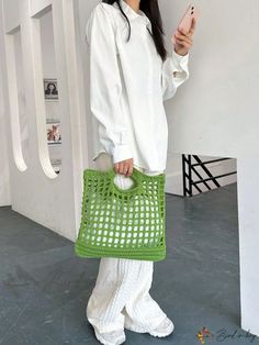 a woman holding a cell phone in her hand and standing next to a white wall