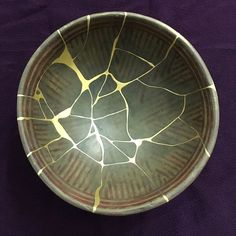 a brown and yellow bowl sitting on top of a purple cloth